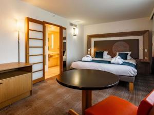 a hotel room with two beds and a table at Novotel Reims Tinqueux in Reims