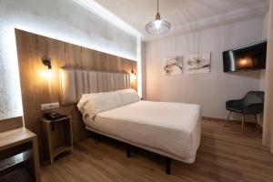 a bedroom with a white bed and a tv at Hotel Sercotel Doña Carmela in Seville