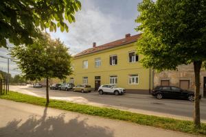 a yellow building with cars parked in a parking lot at Apartment Grof Janko - Luxury in the Center - TERRACE & FREE PARKING in Karlovac