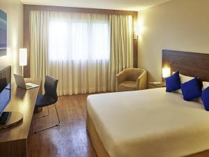 a hotel room with a large bed and a desk at Novotel Manaus in Manaus