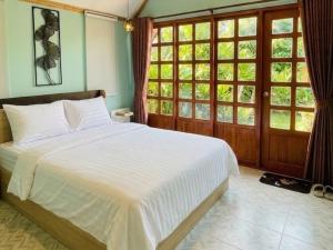 a bedroom with a large white bed and windows at สวนไมตรีจิต รีสอร์ท Suan Maitrichit Resort in Ban Khlong Si