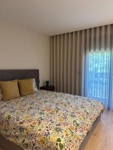 a bedroom with a bed and a window with curtains at Apartamento Cimo da Barca in Ponte da Barca