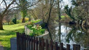 a wooden fence next to a river with flowers at Chambre d'Hôtes Le Moulin Bertrand in Saint-Martin-de-Ribérac