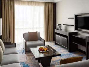 a living room with a television and a table with a bowl of fruit at Swissotel Jeddah Al Hamra in Jeddah