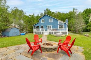 a group of red chairs around a fire pit in front of a blue house at Lakefront Cabin: Kayaks, Paddle Boards & Fishing in Pocono Lake