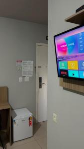 a flat screen tv on a wall next to a door at Mahle Hotel - BR 116, km 48 in Campina Grande do Sul
