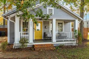 a small white house with a yellow door at Backyard Hangout Firepit Giant Connect 4 & BBQ in Raleigh