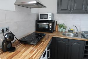 a kitchen with a stove and a microwave at Seacrets Beach House in Praia do Almoxarife