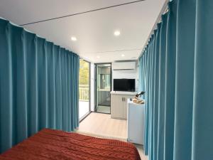 a room with blue curtains and a bed and a television at Hotel Fazenda Parque dos Sonhos in Socorro