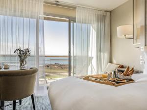 a hotel room with a bed and a table with a tray of food at Sofitel Quiberon Thalassa sea & spa in Quiberon +236 photos