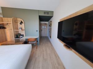a bedroom with a large flat screen tv on a wall at KYRIAD PRESTIGE - PIERRELATTE in Pierrelatte