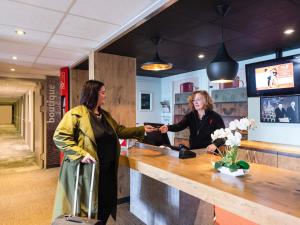 two women standing at a counter in a barber shop at ibis Chalon Sur Saone Nord in Chalon-sur-Saône