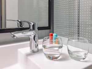 two glasses sitting on a bathroom sink with a faucet at ibis Metz Centre Cathedrale in Metz