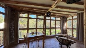a dining room with a table and chairs and windows at Casa de campo Yoga Retreat in Urubamba +64 photos