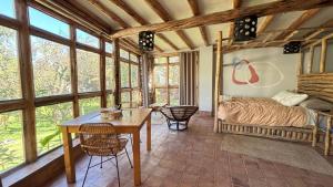 a bedroom with a bed and a table and some windows at Casa de campo Yoga Retreat in Urubamba