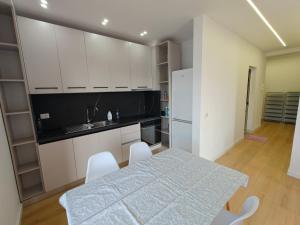 a kitchen with white cabinets and a table and chairs at DfA in Tirana +1 photo