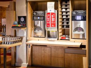 a kitchen with a counter with a coffee maker and a refrigerator at ibis Poitiers Sud in Poitiers