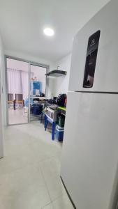 a white refrigerator in a kitchen with a room at Apartamento Confortável na Praia do Morro in Guarapari