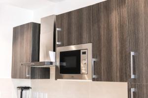 a microwave in a kitchen with wooden cabinets at EMBASSY - Sky Suites in Accra