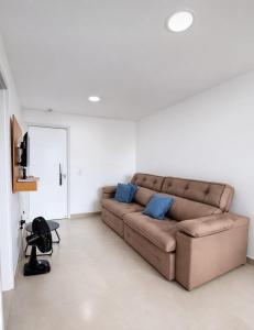 a living room with a brown couch with blue pillows at Apartamento Confortável na Praia do Morro in Guarapari