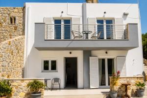 a white house with a balcony and a table at Karies House in Kefalos