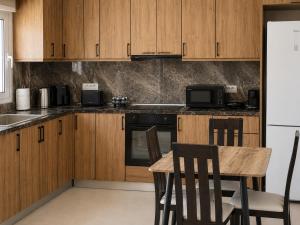 a kitchen with wooden cabinets and a table and a refrigerator at Karies House in Kefalos