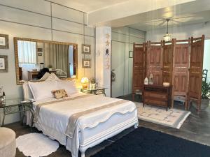a bedroom with a large bed and a mirror at Body & Mind Beautiful - Suites Elegantes e Charmosas in Franca