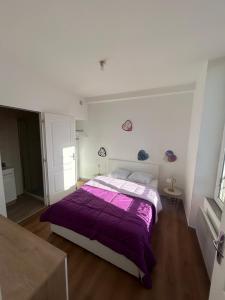 a white bedroom with a purple bed in it at De passage in Nemours