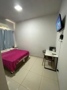 a bedroom with a bed and a table and a tv at Flat aconchegante é silencioso in Rio Verde