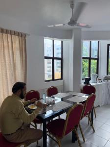 a man sitting at a table in a dining room at ZAN Lodge in Male City
