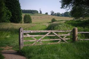 a wooden gate in the middle of a field at Oaters Wood in Petworth