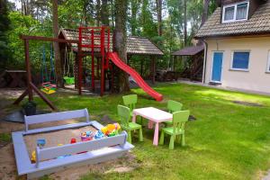 a playground with a table and a red slide at Sztil - Apartamenty i drewniane domki in Pobierowo