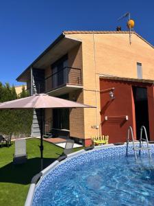 a house with a swimming pool and an umbrella at Vivienda Turística Lorena in Cascante