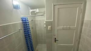 a shower with a white door and a blue shower curtain at Jardim Teresa - Até 10 pessoas, próximo ao Açude Velho, Centro Histórico e Parque do Povo in Campina Grande