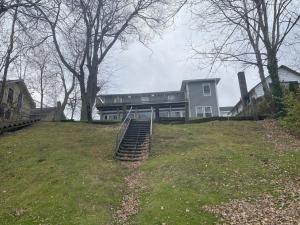 a house on a hill with stairs in front of it at Lake Access Retreat Pet Friendly Fire Pit in Geneva