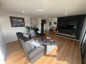 a living room with a couch and a flat screen tv at Derwent Waters Hideway in Austins Ferry