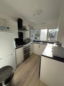 a large kitchen with white appliances and wooden floors at Short Stay & Long Stay home in Ellesmere Port in Little Sutton