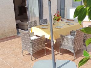 a table with chairs and a yellow tablecloth on a patio at Apartamento La Camelia in Rosal