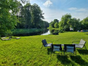 two chairs and a table in a field next to a river at Domki nad rzeką Ełk in Prostki