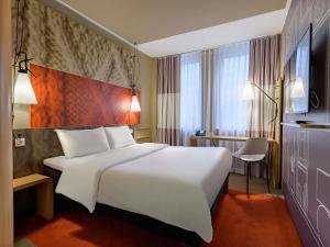 a hotel room with a large white bed and a window at Ibis Hotel Köln Am Dom in Cologne