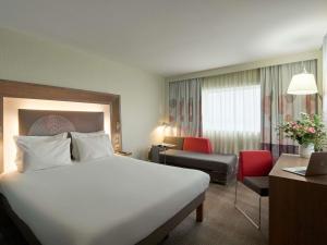 a hotel room with a large white bed and a chair at Novotel Paris La Defense Esplanade in Courbevoie