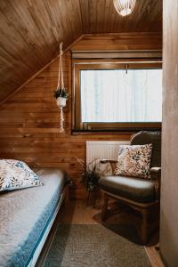 a bedroom with a bed and a chair and a window at Piparmētras in Mērsrags