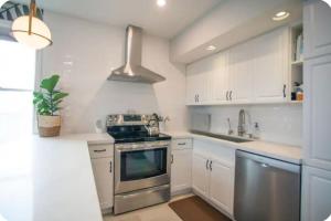 a kitchen with white cabinets and stainless steel appliances at Location Location Location in Stratford +9 photos