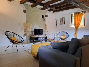 a living room with a couch and chairs and a tv at La Chaumière de Chabine in Oizon