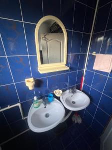 a blue tiled bathroom with a sink and a mirror at Jagoda IN in Otroci