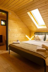 a large bed in a wooden room with a skylight at Meștera 9 in Stînceni
