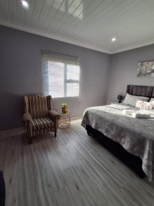 a bedroom with a bed and a chair and a window at Human on Ten BnB in Summer Pride