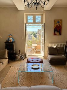 a living room with a chandelier and a glass table at La Brèche - Mansion with swimming pool in Velleron
