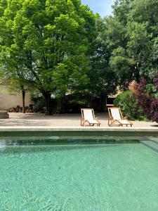 two lounge chairs sitting next to a swimming pool at La Brèche - Mansion with swimming pool in Velleron