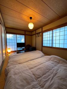 a large white bed in a room with windows at Shirako House in Shirako